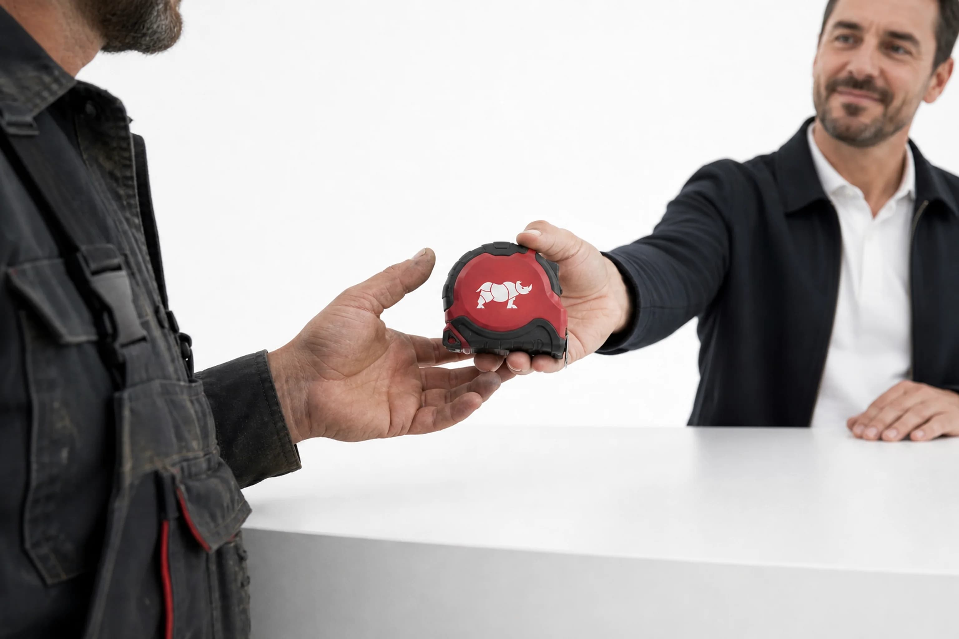 Dispositif distributeurs : au comptoir, un artisan reçoit un mètre ruban rouge Groupe Rhinos en récompense